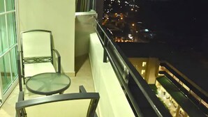 A balcony with a glass table and chairs, overlooking a cityscape at night. - Hotel y Casino Central Park Panama (Panama City)
