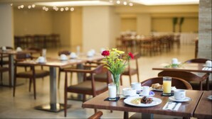 A dining area with tables set for breakfast, including plates of food, cups, and a vase with flowers. - Hotel y Casino Central Park Panama (Panama City)