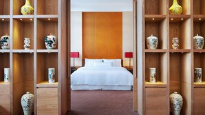 Ein Hotelzimmer mit einem großen Bett, Holzregalen mit dekorativen Vasen und zwei roten Lampen.