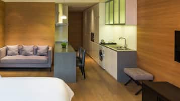 Et moderne hotelværelse med seng, sofa, spiseplads, vaskemaskine og tekøkken.