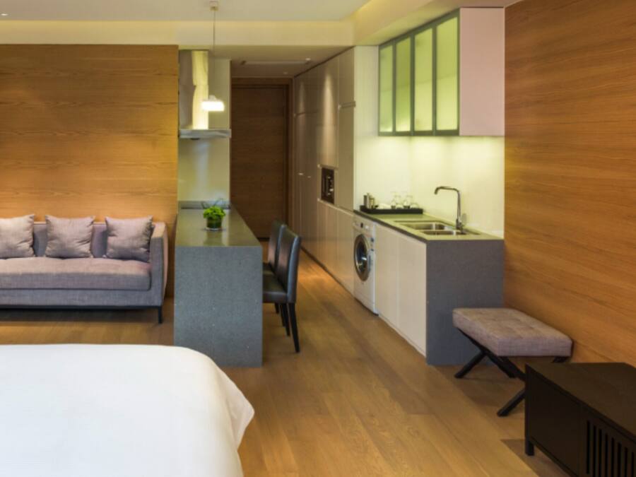 Et moderne hotelværelse med seng, sofa, spiseplads, vaskemaskine og tekøkken.
