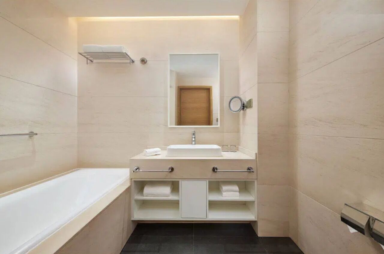 A modern bathroom with a bathtub, a sink with a mirror, and a towel rack.