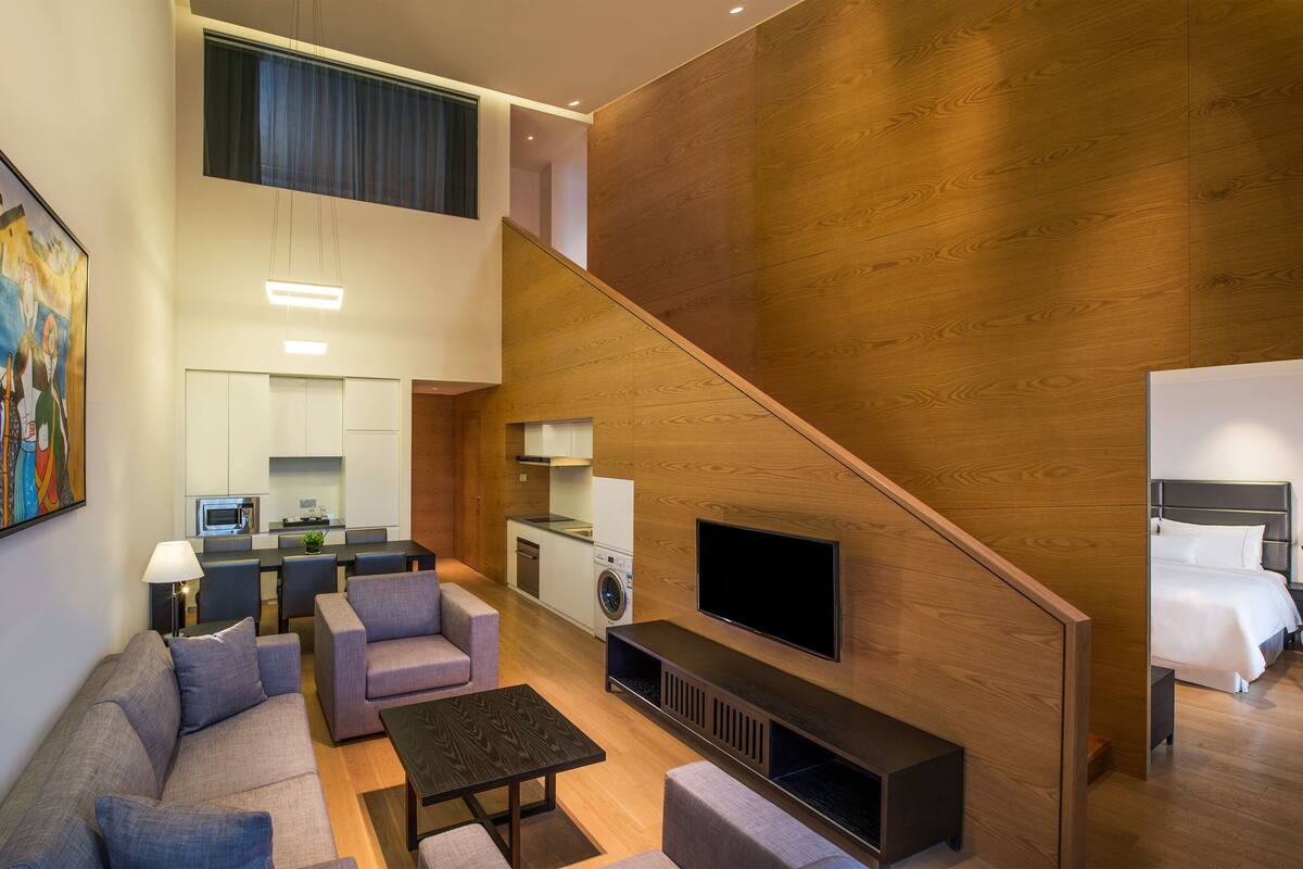 A modern living room with a sofa, a coffee table, and a TV mounted on a wooden wall.