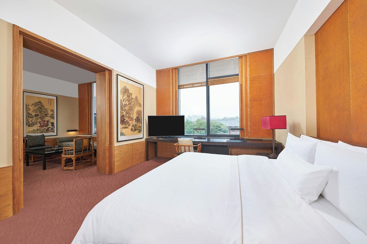 A hotel room with a large bed, a desk with a computer, a television, and artwork on the walls.