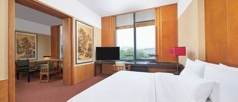 Una habitación de hotel con una cama grande, un escritorio con computadora, televisión y obras de arte en las paredes.