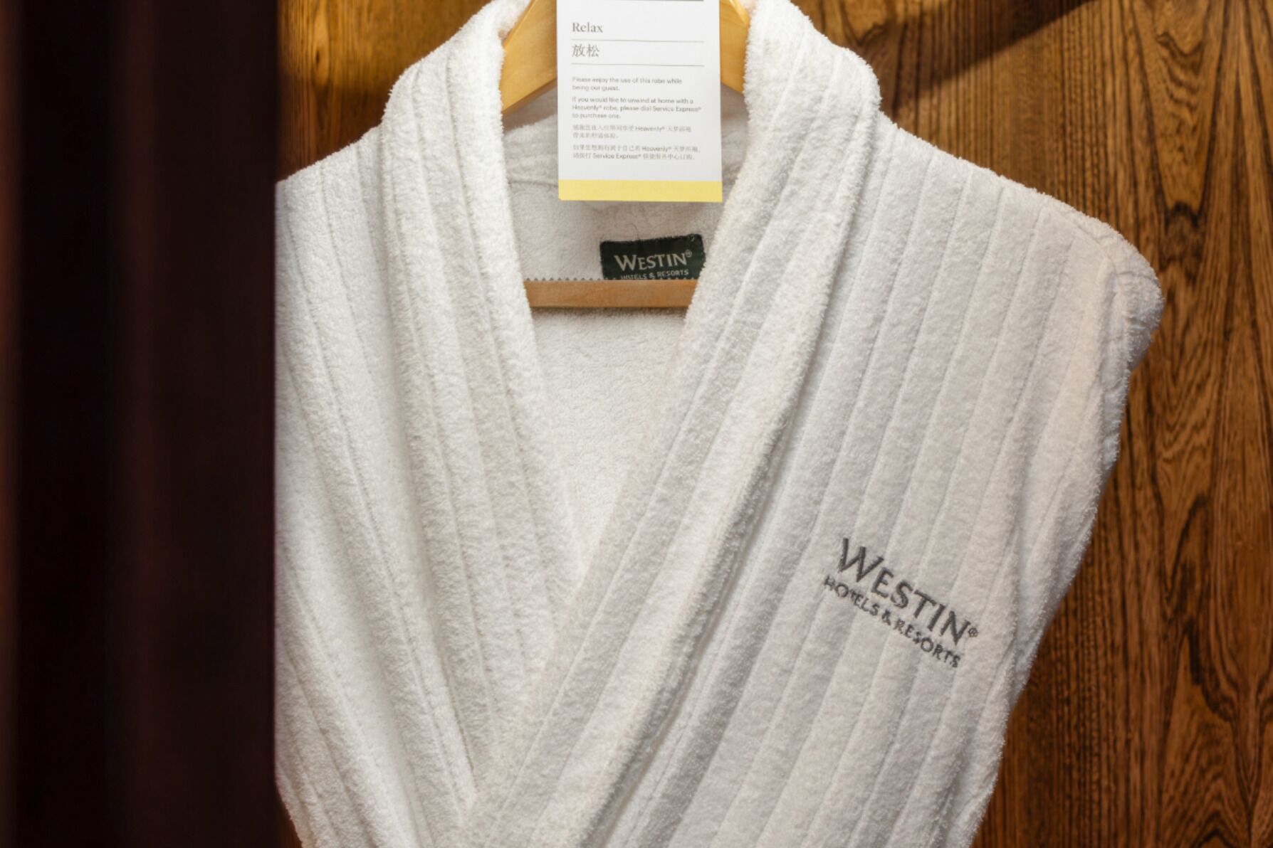 A white towel with the Westin logo and text "Westin Hotels & Resorts" on it, hanging on a wooden hanger.
