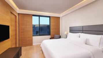 Habitación de hotel moderna con una cama grande, televisor de pantalla plana, paneles de madera y vistas a la ciudad.
