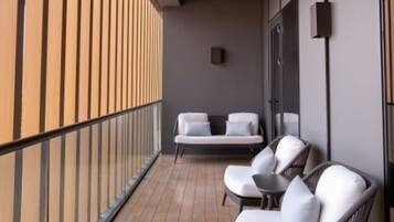 A balcony with a seating area, a small table, and a wall-mounted device.