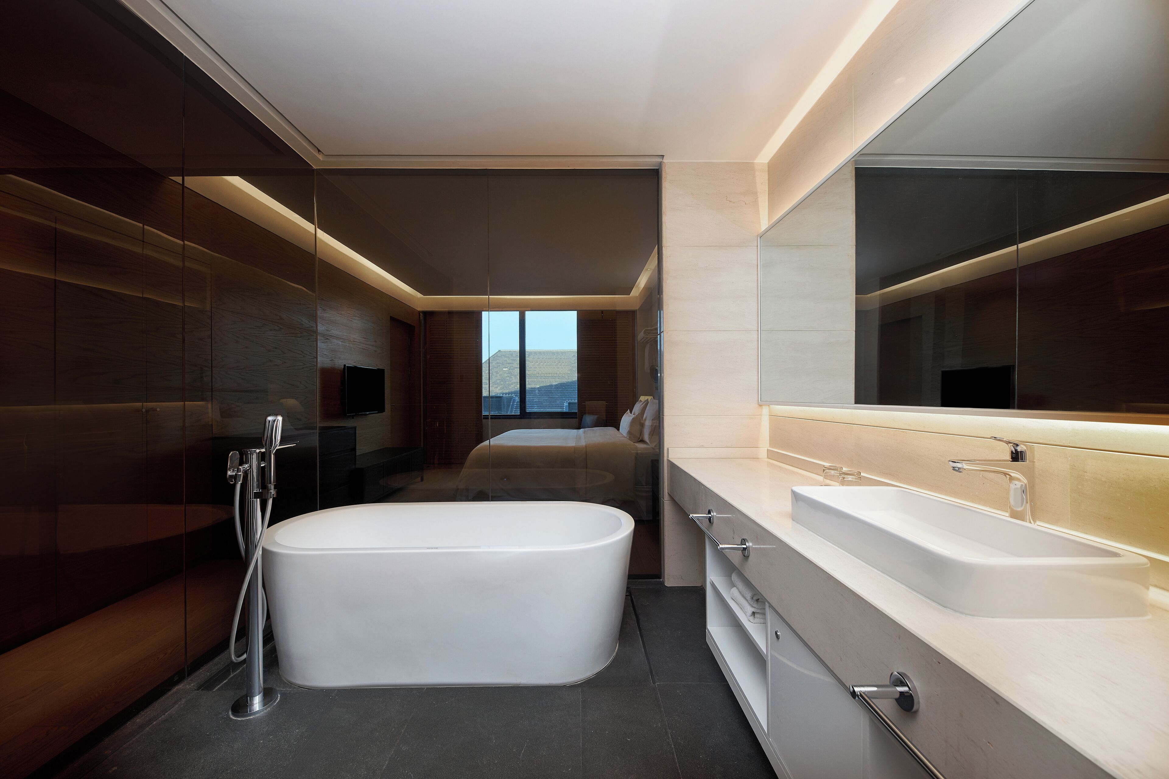A modern bathroom with a freestanding bathtub, a large mirror, and a vanity with a sink.