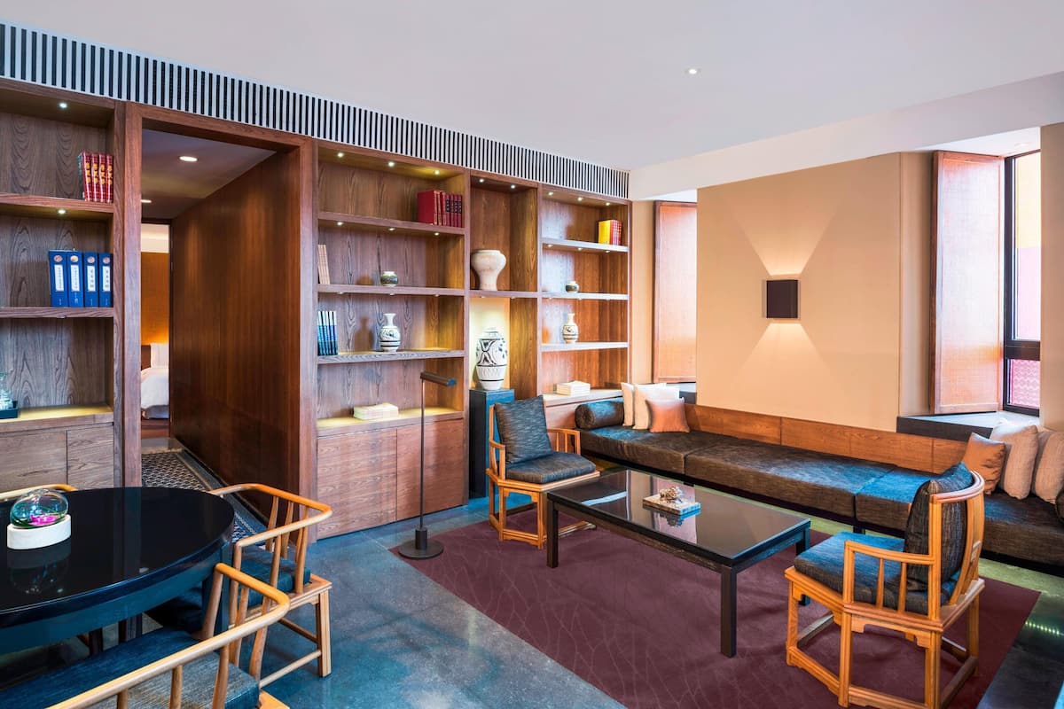 A modern living room with a sectional sofa, wooden shelves, and a glass coffee table.