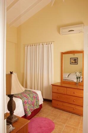 Ein Schlafzimmer mit einem Bett, einem Schminktisch, einem Spiegel und einem Fenster mit Vorhängen.