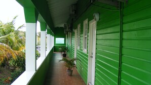 Un pasillo verde con suelo de baldosas, plantas en macetas y una puerta al final.