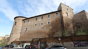 A historic building with a brick facade, multiple windows, and a turret. - Maison Colosseo (Rome)