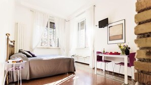 A modern bedroom with a bed, bedside table, and a desk with chairs. - Maison Colosseo (Rome)
