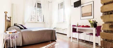 A modern bedroom with a bed, bedside table, and a desk with chairs.