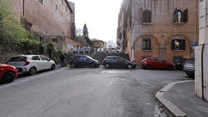 A narrow street with parked cars and buildings on either side. - Maison Colosseo (Rome)