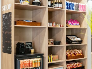 Un magasin dont les étagères sont remplies d’en-cas, de boissons et où l’on trouve une machine à café.