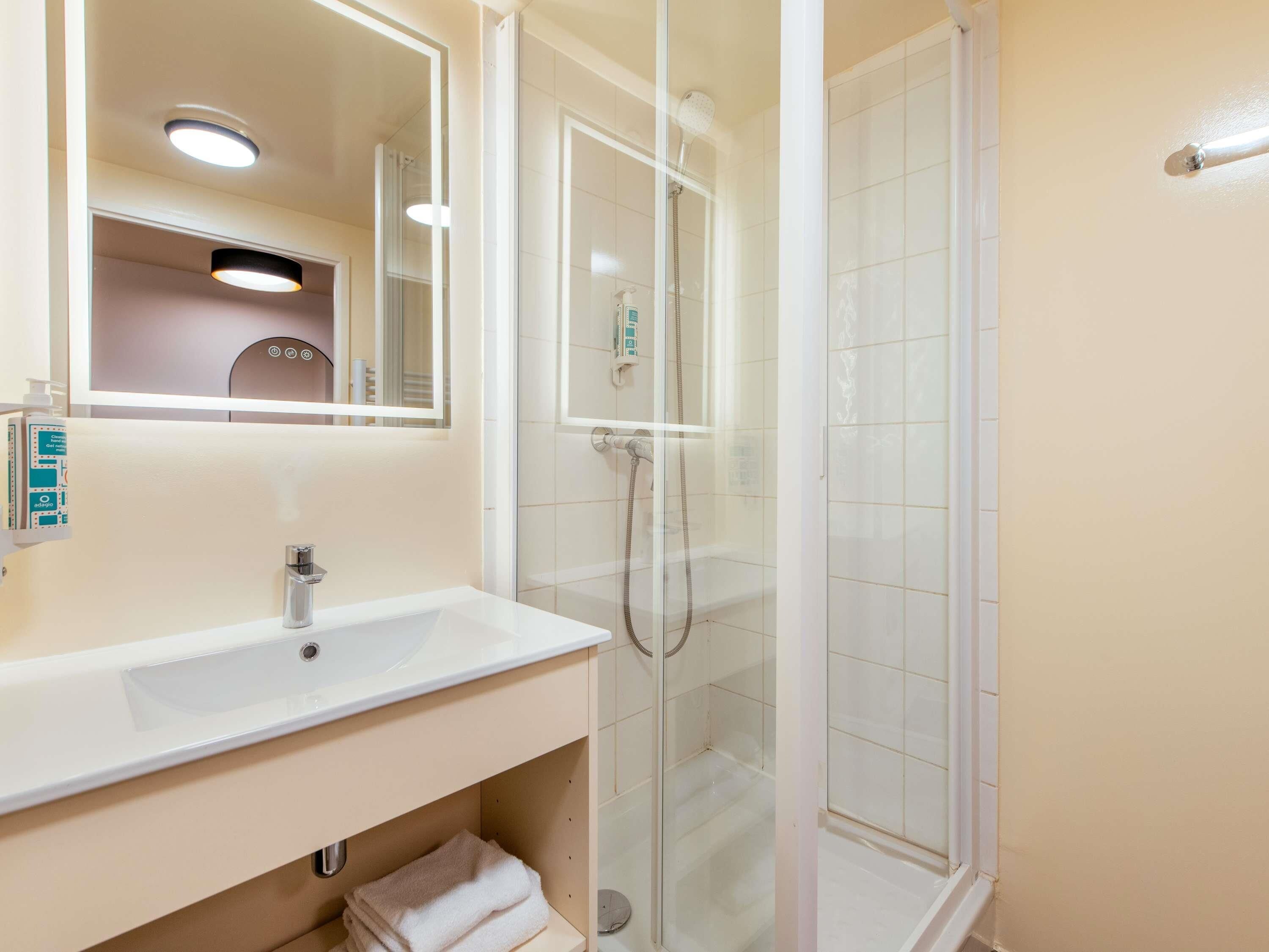 Een badkamer met een wastafel, spiegel en douchecabine.