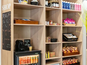 Un magasin dont les Ă©tagĂšres sont remplies dâen-cas, de boissons et oĂč lâon trouve une machine Ă cafĂ©.