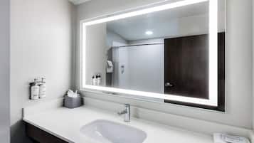 A modern bathroom with a large mirror, a sink, and toiletries.