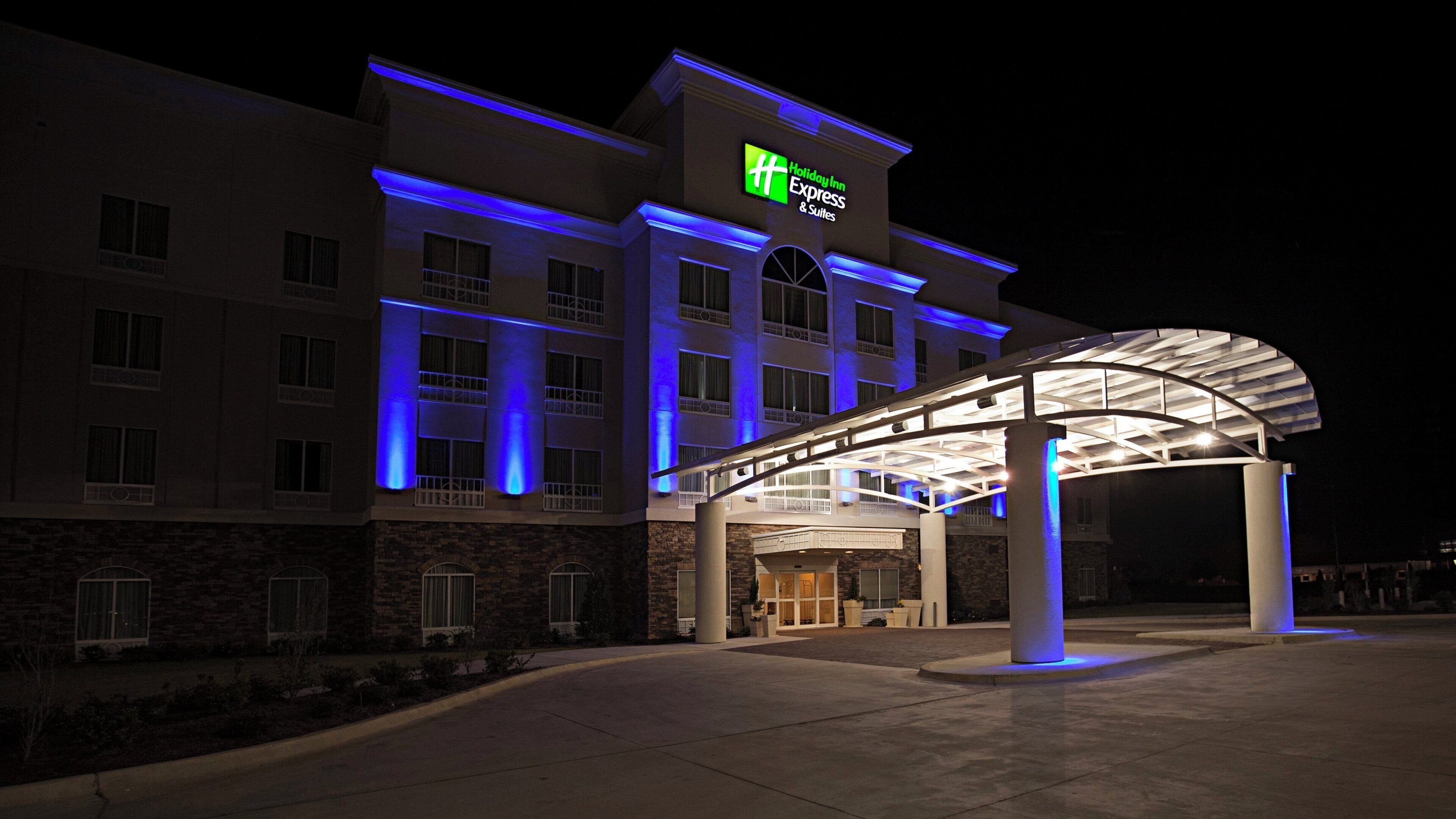 A Holiday Inn Express & Suites hotel with a covered entrance and blue lighting.