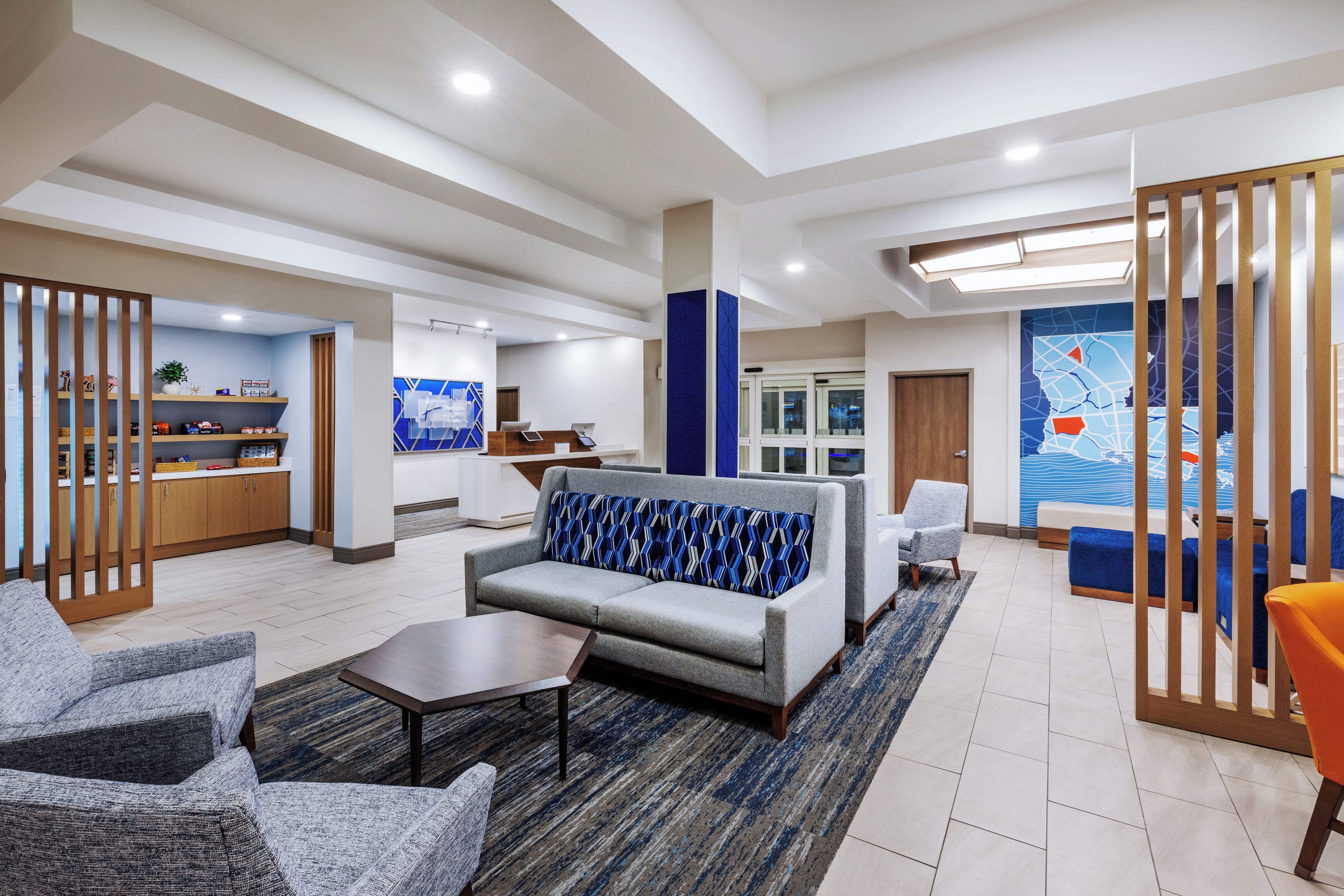 A modern hotel lobby with a reception desk, seating area, and a large window with a cityscape view.