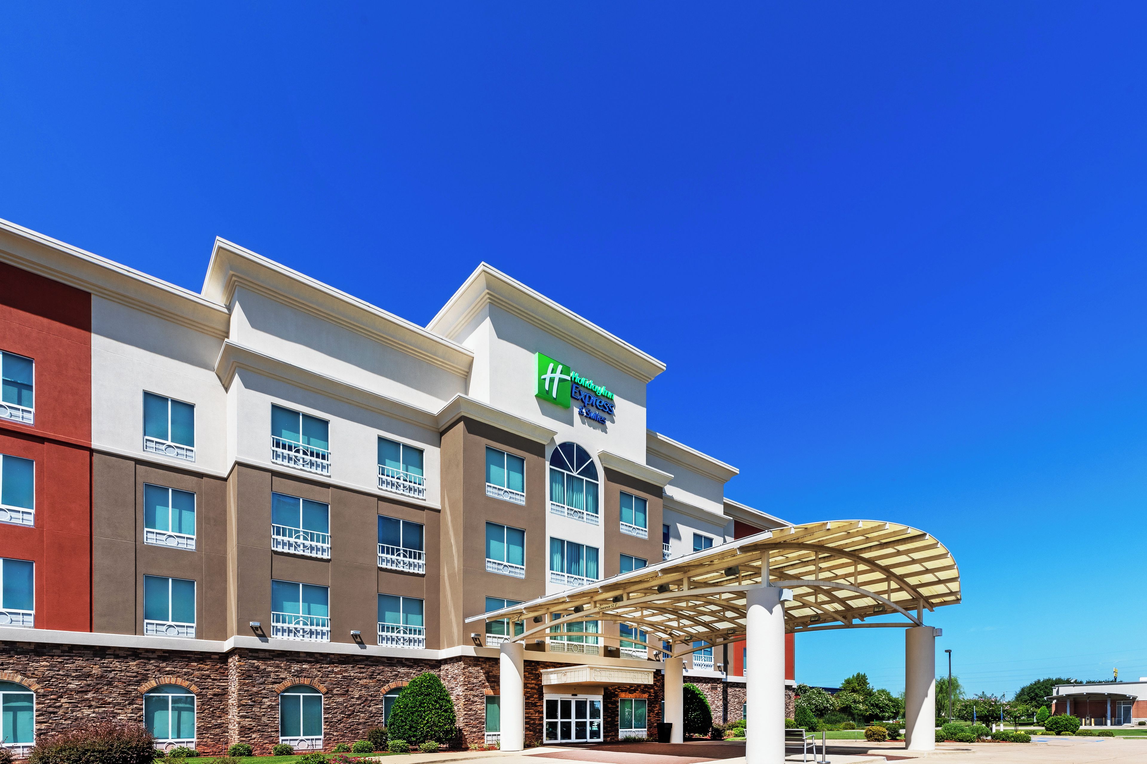 Un hôtel à plusieurs étages, reconnaissable à son grand panneau vert indiquant qu’il s’agit d’un hôtel de la chaîne Wyndham Express.