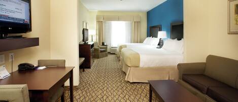 A hotel room with a bed, a desk, a television, and a seating area.