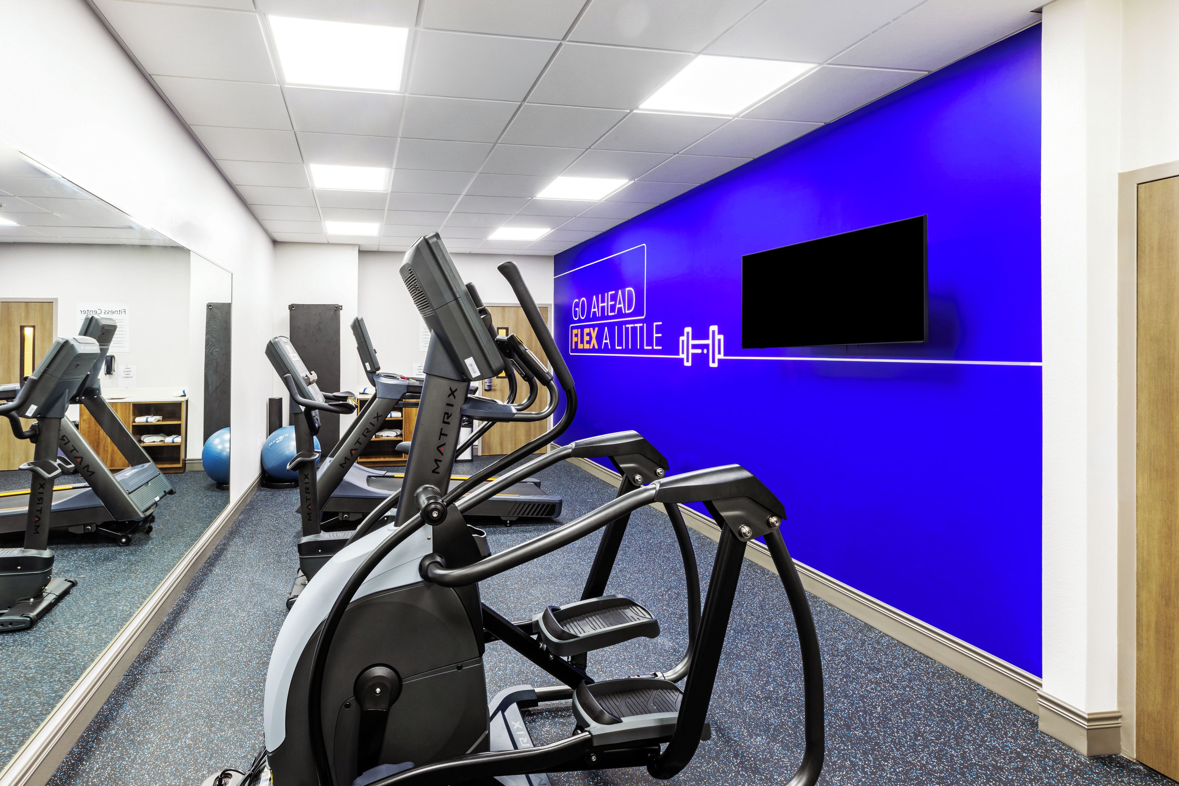 A gym with treadmills, stationary bikes, and exercise balls.