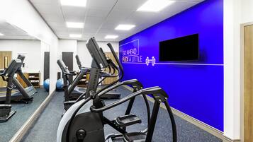 A gym with treadmills, stationary bikes, and exercise balls.