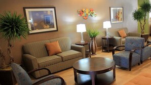 A living room with a sofa, armchairs, a coffee table, and a lamp. - Holiday Inn Express Hotel & Suites Bossier City - Louisiana by IHG (Bossier City)