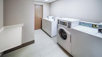 Un lavadero con lavadora, secadora y cestos apilados para ropa.