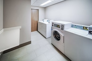 Une buanderie équipée d’un lave-linge, d’un sèche-linge et de paniers à linge empilés.