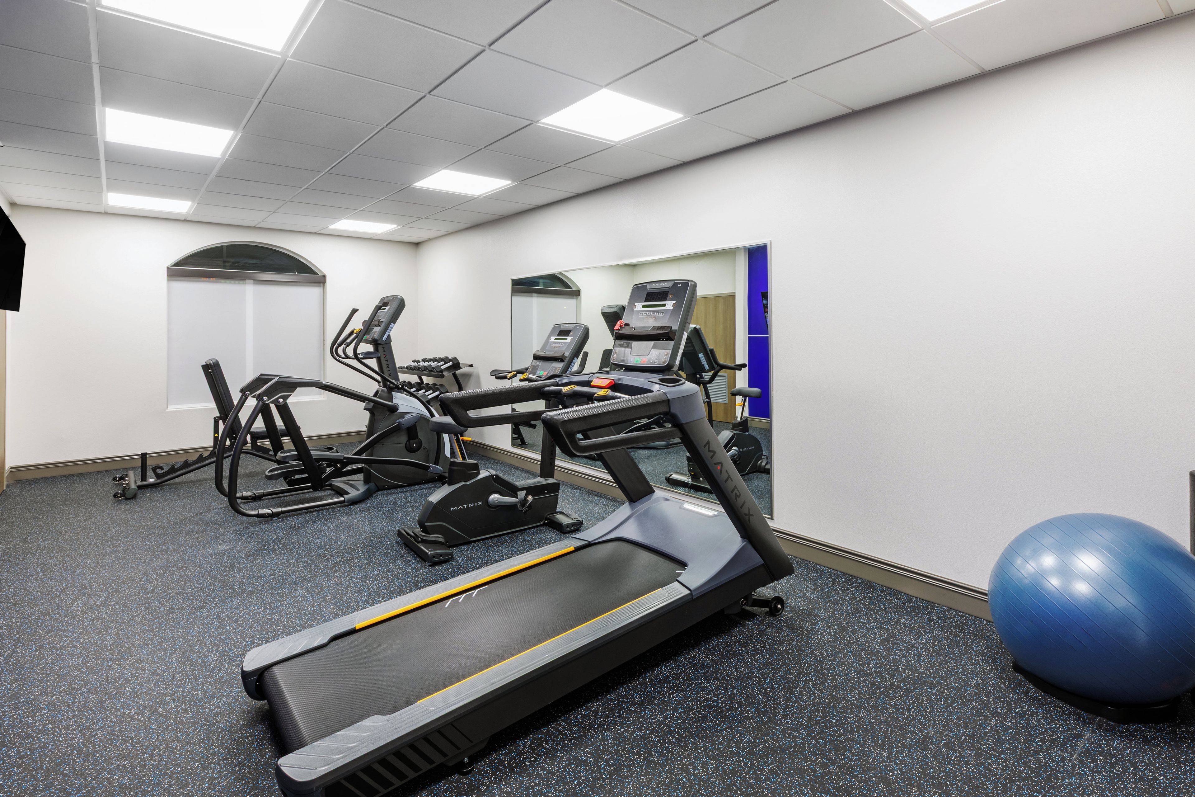 Un gimnasio equipado con cintas de correr, una bicicleta estática y una máquina de remo.