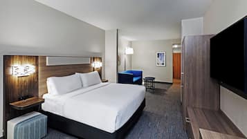 A hotel room with a bed, bedside tables, a desk, a chair, a TV, and a wall-mounted artwork.