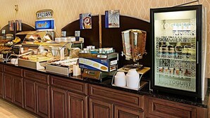 A buffet counter with various food items, including a display of yogurt and milk cartons, and a sign for 'Express Short'. - Holiday Inn Express Hotel & Suites Bossier City - Louisiana by IHG (Bossier City)