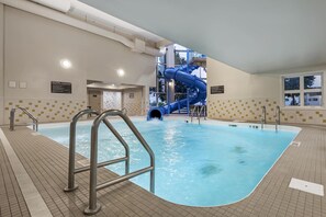 An indoor swimming pool with a blue water slide and a shower area.