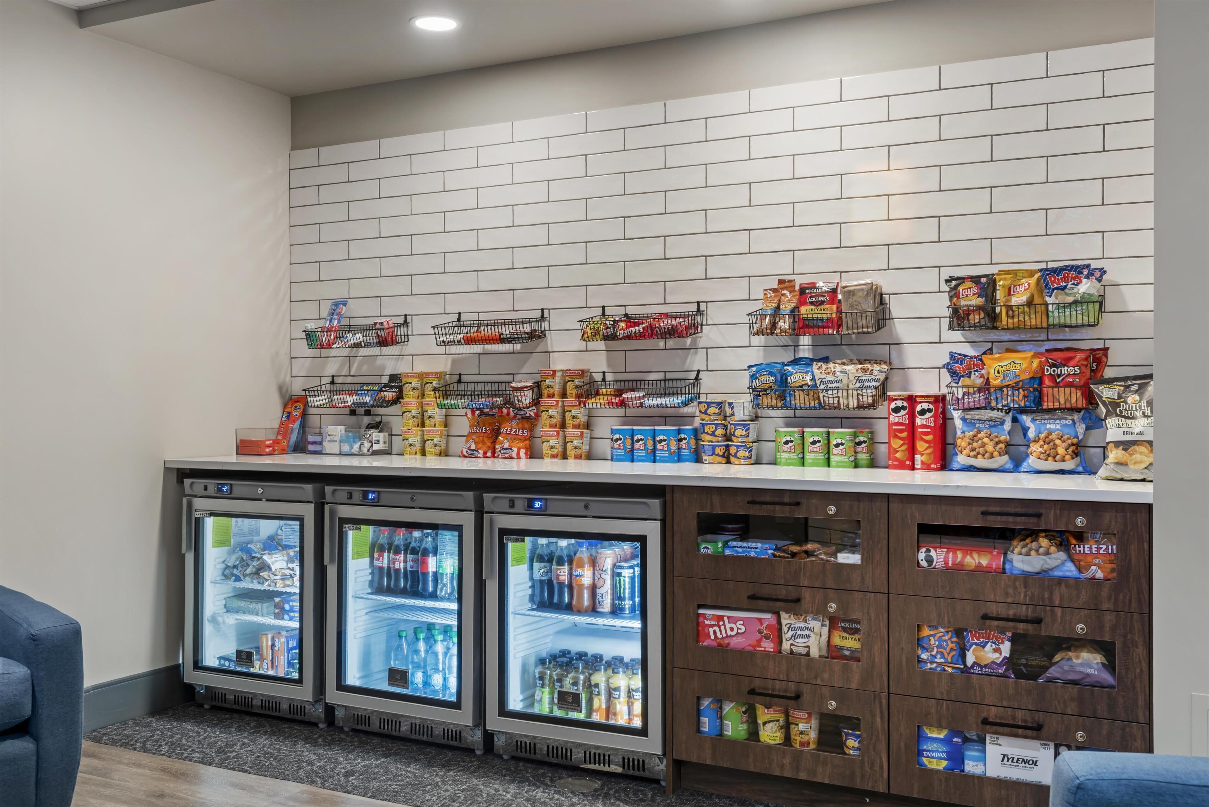 Un bar de aperitivos con una variedad de productos envasados, bebidas y tres vitrinas refrigeradas.