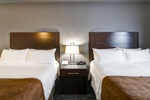 A hotel room with two beds, a nightstand with a lamp, and a digital clock. - Best Western Plus Brandon Inn (Brandon)