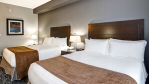A hotel room with two beds, a nightstand with a lamp, a framed picture on the wall, and a carpeted floor. - Best Western Plus Brandon Inn (Brandon)