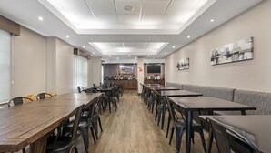 A spacious dining area with multiple tables and chairs, a counter with a display, and artwork on the walls.
