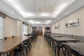 A spacious dining area with multiple tables and chairs, a counter with a display, and artwork on the walls.