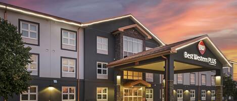 Een hotel met een overdekte ingang, meerdere ramen en een bord met 'Best Western PLUS'.
