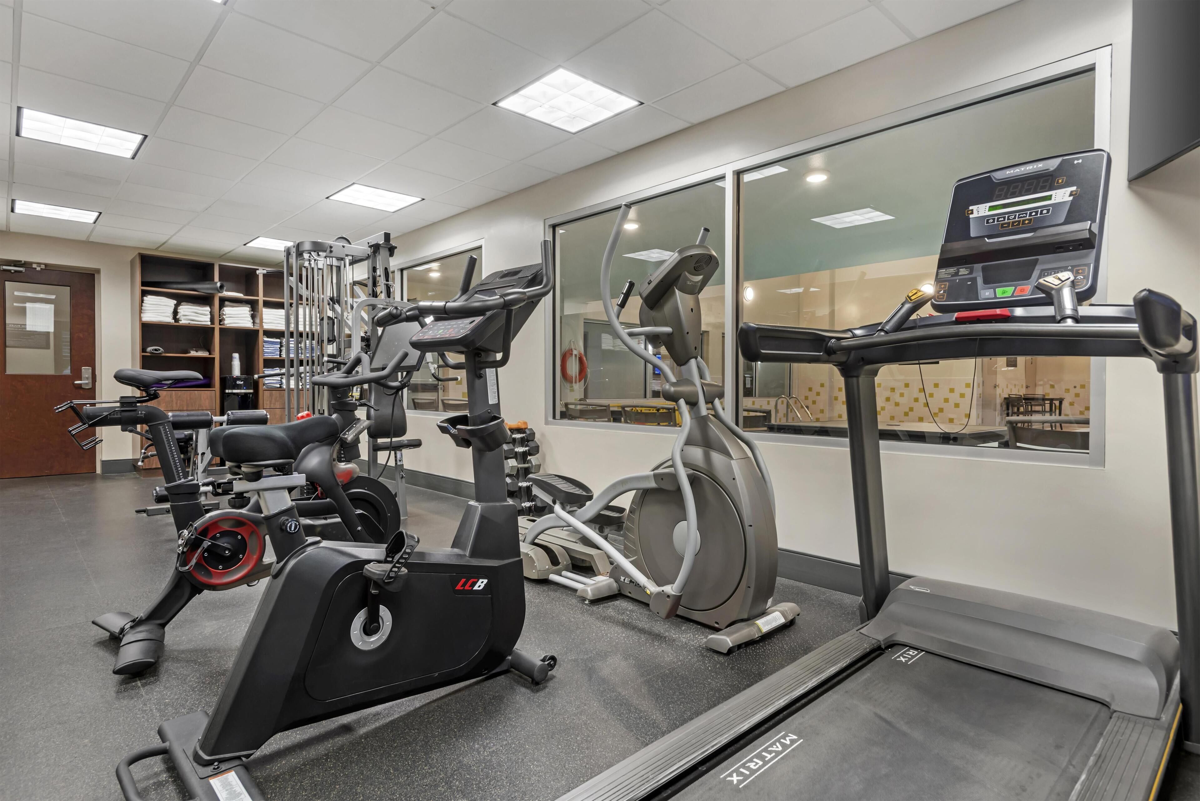 Une salle de sport équipée de machines de cardio, de matériel de musculation et d’un tapis de course.