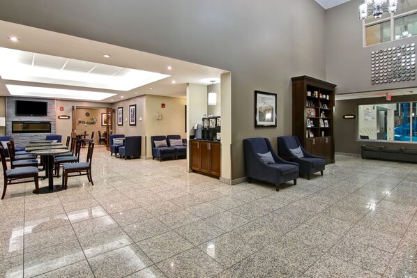 A spacious lobby with a reception desk, seating area, and a large bookshelf. - Best Western Plus Brandon Inn (Brandon)