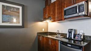 A kitchen with wooden cabinets, a stainless steel microwave, a coffee maker, and a dishwasher. - Best Western Plus Brandon Inn (Brandon)