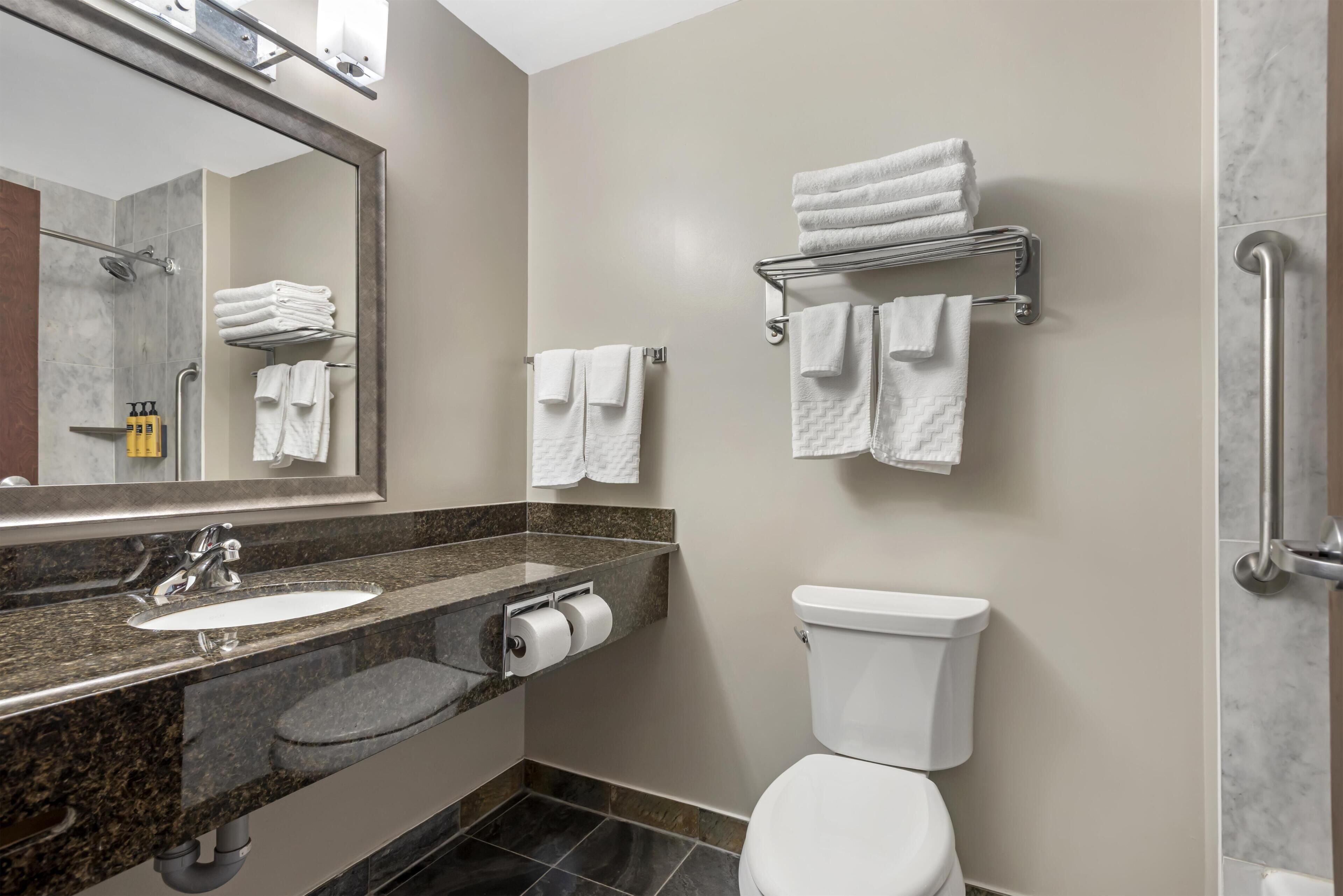 A modern bathroom with a marble sink, a toilet, and a towel rack.