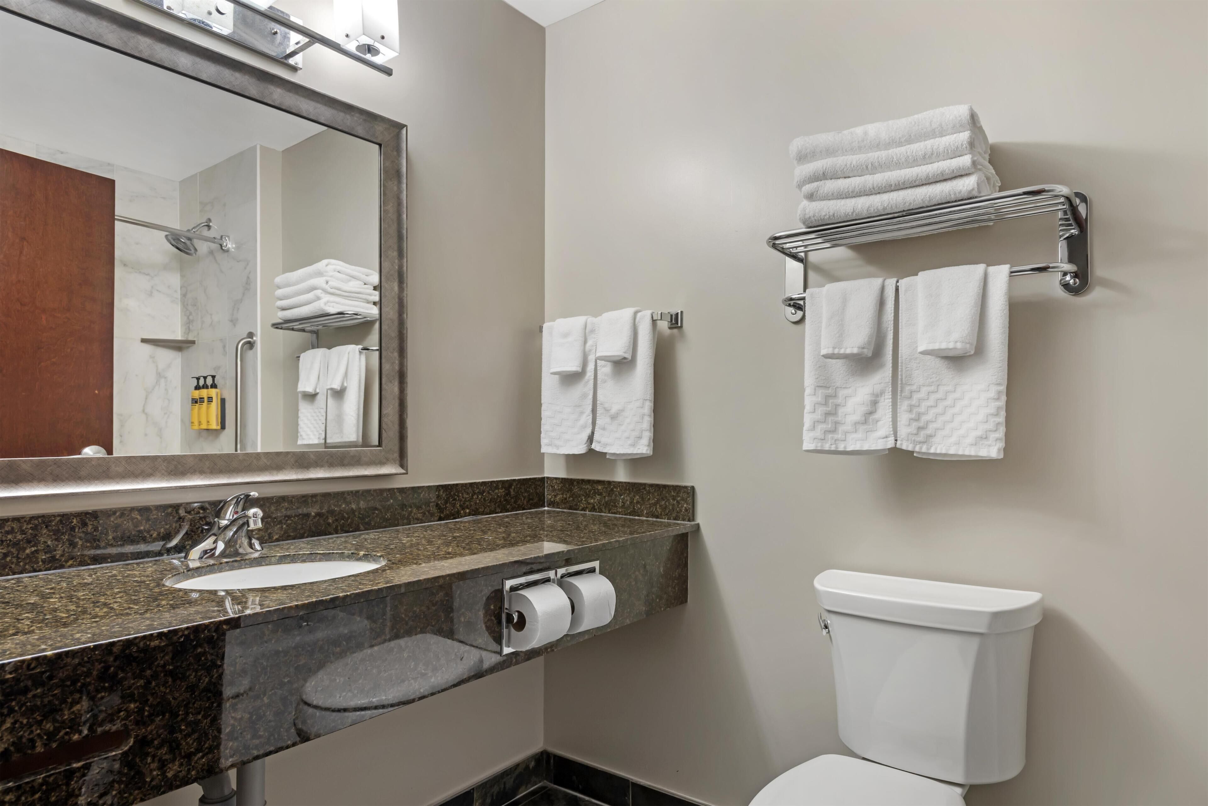 A modern bathroom with a marble sink, a toilet, and a towel rack.