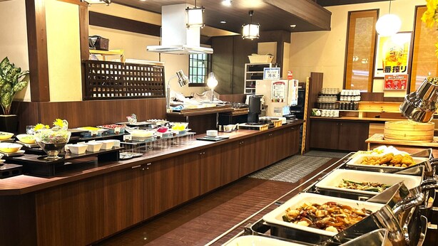 En buffet med forskellige madstationer, kaffemaskine og vanddispenser.