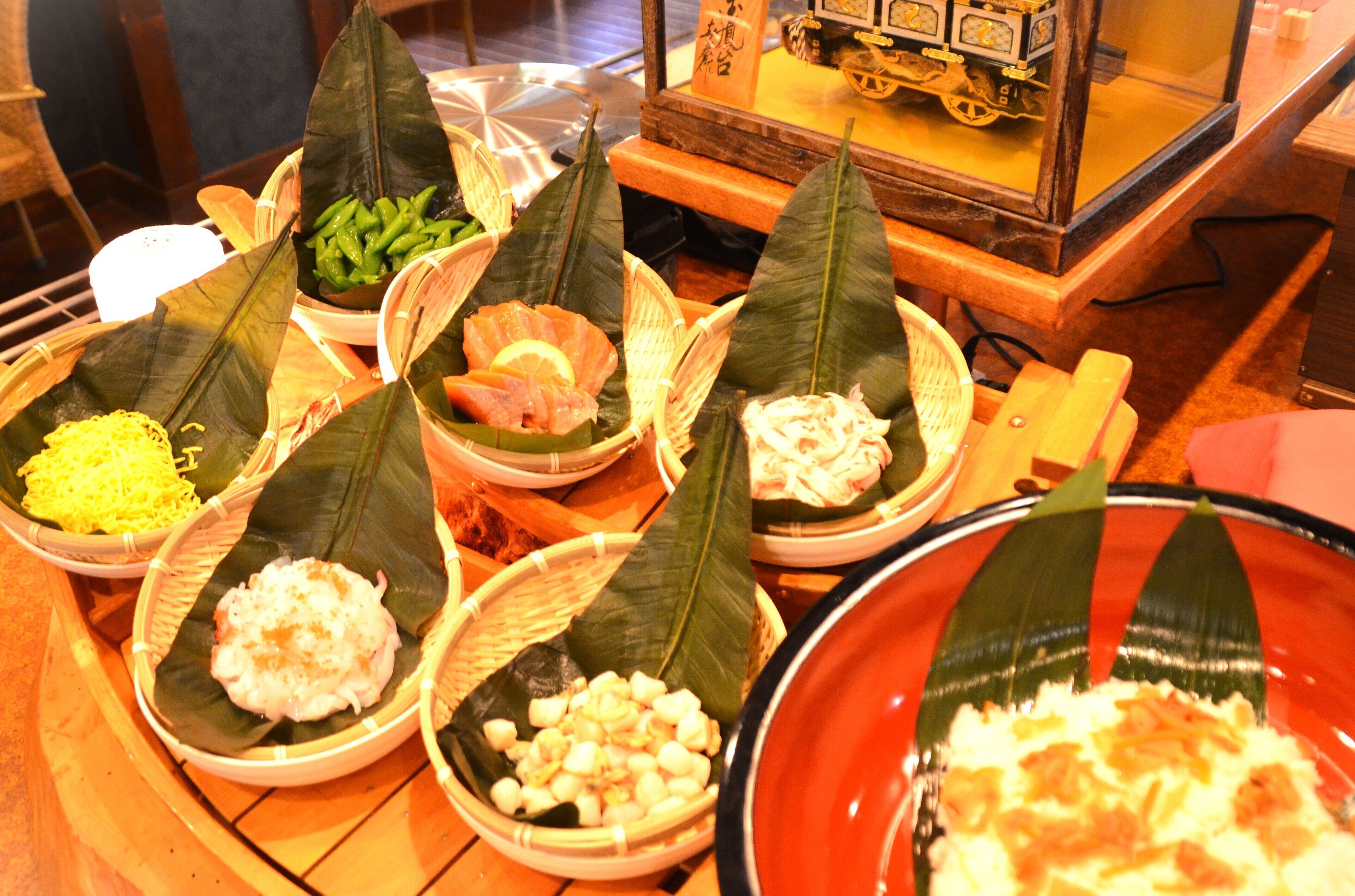 A variety of dishes served on banana leaves, including rice, vegetables, and possibly seafood, displayed on a wooden table.